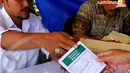 Petugas KPPS memberikan surat suara yang sudah ditandai stempel bertuliskan Pemilu Ulang kepada warga Depok yang akan menggunakan hak politiknya pada Minggu (13/4/2014). (Liputan6.com/Miftahul Hayat)