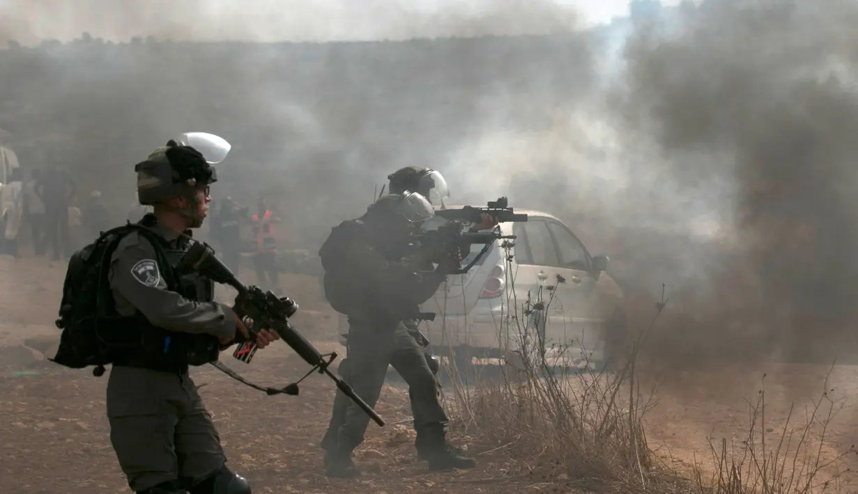 Pasukan penjaga perbatasan Israel membidik saat bentrok dengan pengunjuk rasa Palestina di Ramallah, Tepi Barat, Kamis (17/10/2019). Pengunjuk rasa menentang pembangunan pos terdepan Israel di dekat desa Palestina, Turmus Ayya, dan pemukiman Israel, Shilo. (JAAFAR ASHTIYEH/AFP)