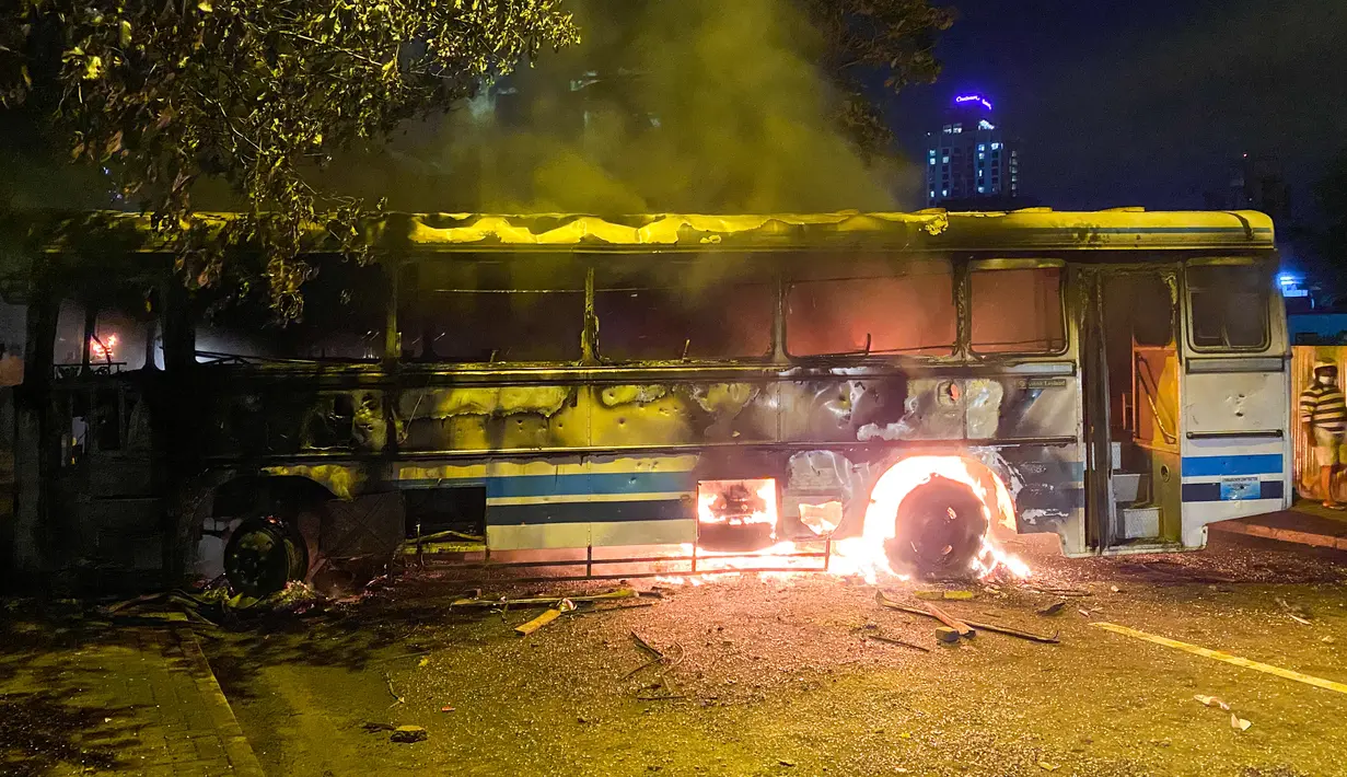 <p>Sebuah bus terbakar di dekat kediaman resmi Perdana Menteri Mahinda Rajapaksa yang akan keluar dari Sri Lanka, di Kolombo pada 9 Mei 2022. Puluhan bus yang digunakan oleh loyalis Rajapaksa untuk melakukan perjalanan ke Kolombo pada hari sebelumnya dibakar atau rusak di seluruh negeri. (ISHARA S. KODIKARA / AFP)</p>