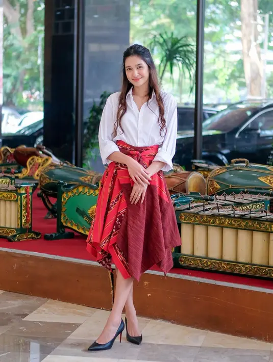 Bertugas dalam serangkaian seminar kepemudaan Kemenpora,  Mikha tampil elegan dengan kemeja panjang warna putih yang dipadukan dengan tenun skirt dress dari okainku.