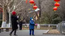 Seorang anak laki-laki yang mengenakan masker menerbangkan layang-layang dekat pohon berhias lentera di taman umum saat liburan Tahun Baru Imlek di Beijing, China, Kamis (26/1/2023). (AP Photo/Mark Schiefelbein)