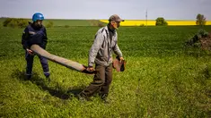 Seorang petani dan anggota tim ranjau dari Layanan Darurat Negara Ukraina membawa rudal yang belum meledak yang tersisa di dekat desa Hryhorivka, Wilayah Zaporizhzhia, pada 5 Mei 202. Musim tanam tahun ini petani membutuhkan lebih dari bahan bakar dan pupuk. Kini, mereka juga membutuhkan jaket antipeluru dan ranjau untuk menghancurkan bom yang tersebar di ladang mereka. (Dimitar DILKOFF / AFP)