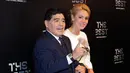 Diego Maradona bersama kekasihnya, Rocio Oliva berpose saat tiba menghadiri The Best FIFA Football Awards 2017 di London, Inggris (23/10). Rocio berusia 23 tahun  merupakan kekasih Maradona sejak lebih dari 3 tahun lalu. (AP Photo/Alastair Grant)