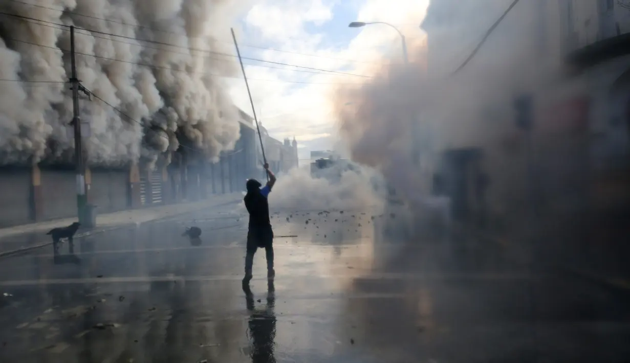 Pengunjuk rasa memegang besi berukuran panjang saat bentrok dengan polisi hara di sekitar Kongres di Valparaiso, Chili. Sabtu (21/5). Sejumlah gedung terbakar dan seorang polisi tewas dalam peristiwa tersebut. (AFP Photo/Claudio Reyes)