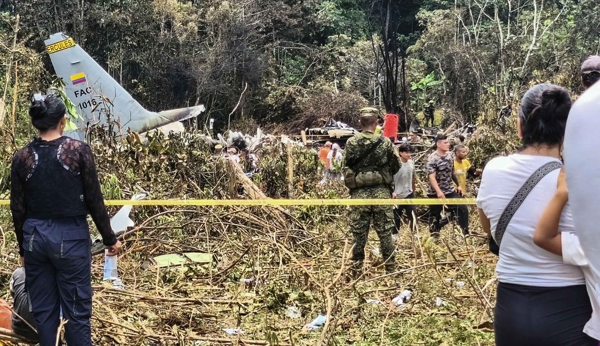 Komandan Angkatan Udara Kolombia, Jenderal Carlos Silva, mengatakan bahwa pesawat itu mengangkut 114 penumpang dan 11 awak. Tampak dalam foto, warga dan tentara berdiri di dekat puing-puing pesawat Hercules Angkatan Udara yang jatuh saat lepas landas, di Puerto Leguizamo, Kolombia, dekat perbatasan selatan dengan Ekuador, pada 23 Maret 2026. (Daniel Ortiz/AFP)
