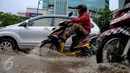 Kendaran roda dua dan empat menerjang genangan air di kawasan Kuningan, Jakarta, Selasa (24/11). Jalur lambat di Jalan HR Rasuna Said, Kuningan, tampak dihindari pengendara karena terdapat genagan air setinggi 20 cm. (Liputan6.com/Faizal Fanani)