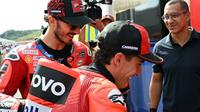 Pembalap MotoGP Spanyol dari Tim Ducati Lenovo, Marc Marquez (tengah), dan rekan setimnya dari Italia, Francesco Bagnaia (kiri), berjalan menuju pit sebelum sesi pemanasan MotoGP Grand Prix Jepang di Mobility Resort Motegi, Motegi, Prefektur Tochigi, pada 28 September 2025. (Toshifumi KITAMURA/AFP)