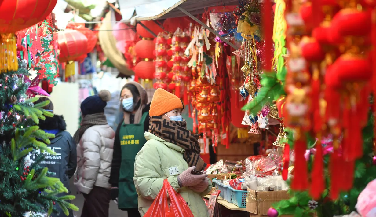 Seorang wanita membeli pernak-pernik dekorasi menjelang Hari Tahun Baru di sebuah pasar di Qingdao, di provinsi Shandong timur China pada 25 Desember 2022. Warga China mulai berburu pernak-pernik Tahun Baru seperti lampion, kartu tahun baru, baju, dan hiasan rumah. (AFP/STR)