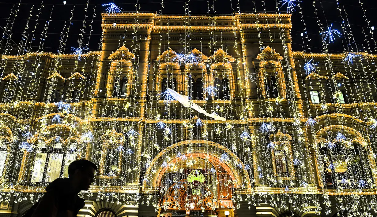 Pejalan kaki melewati toserba GUM dengan dekorasi lampu yang menghiasi sebuah jalan pusat kota Moskow, Senin (18/12). Salah satu sudut kota di Rusia itu didekorasi dengan lampu dan pernak-pernik perayaan Natal dan Tahun Baru. (AFP PHOTO / Yuri KADOBNOV)