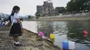 Saki Morioki, 5 tahun, menyaksikan lampion kertas melayang di sepanjang Sungai Motoyasu di depan Kubah Bom Atom di Hiroshima, Jepang barat, Kamis (6/8/2020). (AP Photo/Eugene Hoshiko)