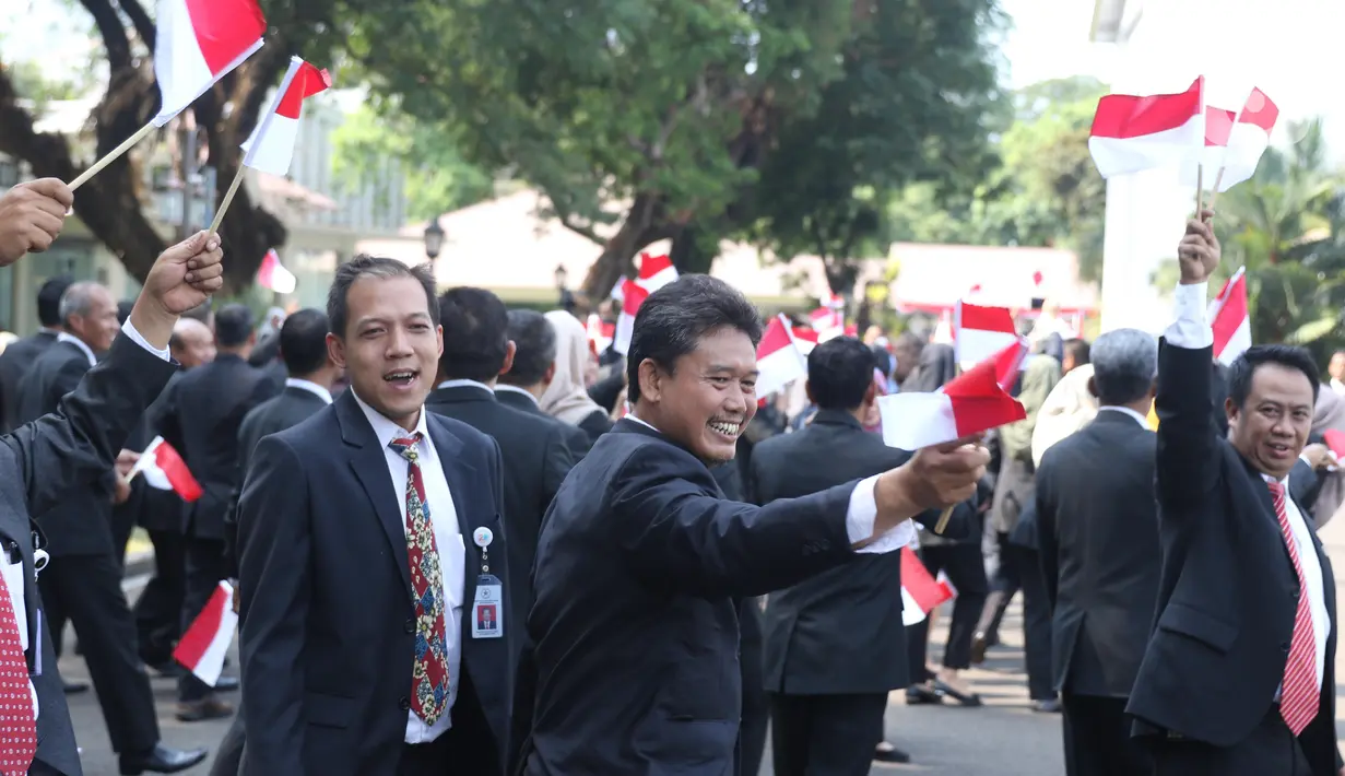Pegawai Istana mengibarkan bendera merah putih saat rombongan mobil Presiden terpilih Joko Widodo (Jokowi)  melintas menuju gedung DPR di Istana Kepresidenan, Jakarta, Minggu (20/10/2019). Jokowi-Ma'ruf Amin kembali dilantik sebagai Presiden-Wapres RI periode 2019-2024. (Liputan6.com/Angga Yuniar)
