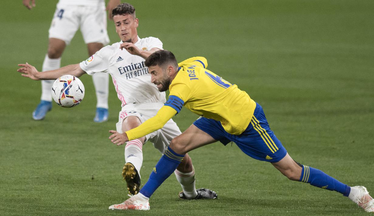 Pemain Real Madrid, Antonio Blanco, berebut bola dengan pemain Cadiz, Jose Mari, pada laga Liga Spanyol di Stadion Ramon de Carranza, Rabu (22/4/2021). Real Madrid menang dengan skor 3-0. (AFP/Jorge Guerrero)
