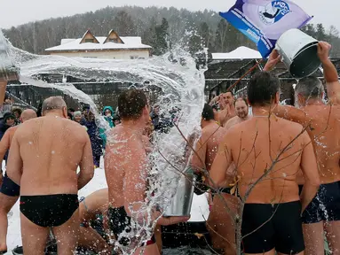 Para anggota klub perenang musim dingin menyiramkan air dingin ke satu sama lain saat perayaan hari Polar Bear, Krasnoyarsk, Rusia (27/11). Mereka bertelanjang di dinginnya salju, dengan suhu udara sekitar minus 5 derajat Celsius. (Reuters/Ilya Naymushin)