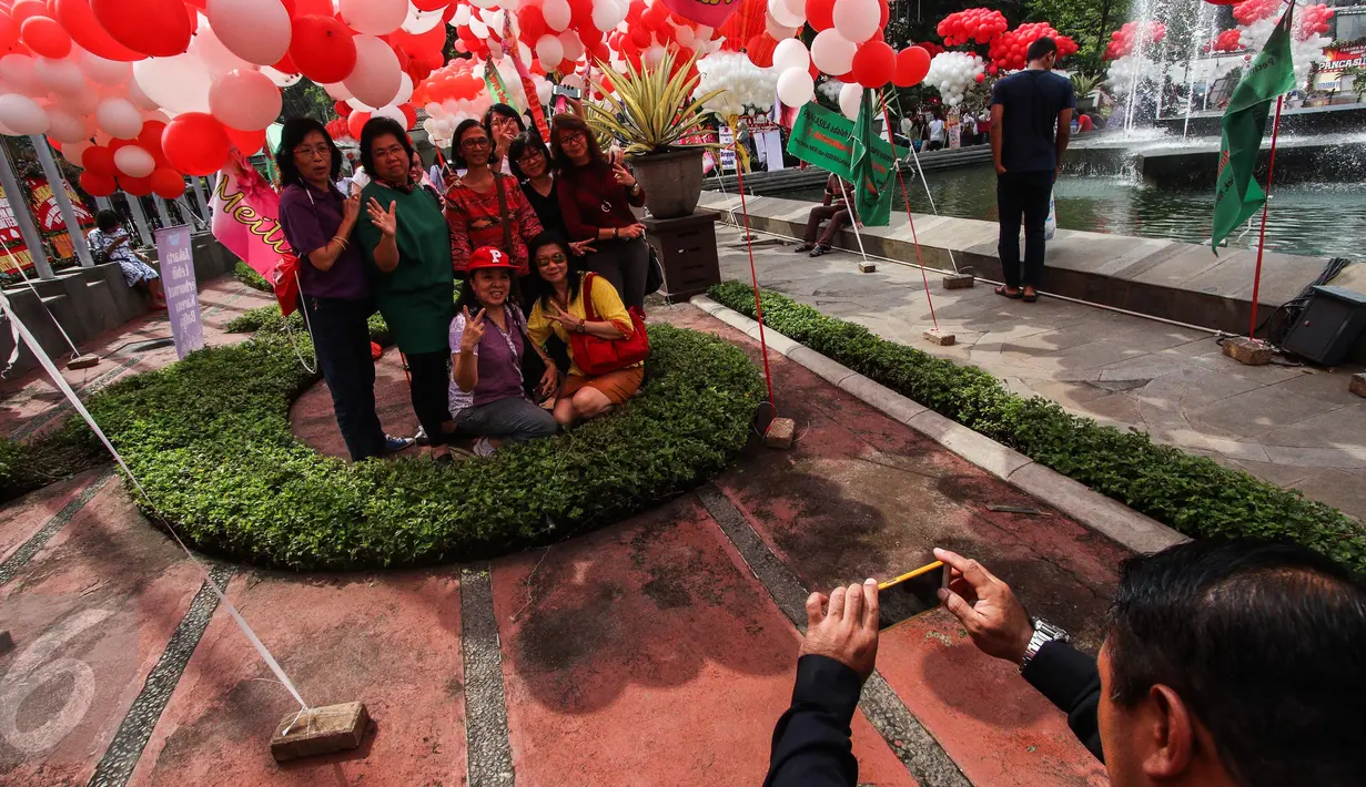 Sejumlah warga berfoto dengan balon berwarna merah putih yang menghiasi halaman Balai Kota, Jakarta, Senin (8/5). Selain sebagai dukungan balon itu juga sebagai bentuk terima kasih atas kinerja Ahok-Djarot. (Liputan6.com/Faizal Fanani)
