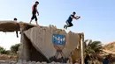 Pemuda Suriah melakukan olahraga ekstrem parkour di atas reruntuhan bangunan yang hancur akibat serangan pasukan rezim di kota Binnish di provinsi barat laut Idlib pada 17 Juni 2020. Parkour merupakan olahraga ketangkasan yang terdiri dari lari, melompat, salto dan berayun. (Abdulaziz KETAZ / AFP)