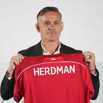 Sebagai informasi, John Herdman datang ke Indonesia dengan membawa sejumlah pengalaman sukses, terutama saat bertugas di Kanada. Dia mengantar timnas putri Kanada meraih dua medali perunggu berturut-turut dalam Olimpiade 2012 dan 2016. Tampak dalam foto, pelatih kepala tim nasional sepak bola Indonesia yang baru, John Herdman memegang jersey tim yang bertuliskan namanya saat konferensi pers di Jakarta, Selasa 13 Januari 2026. (AP Photo/Achmad Ibrahim)