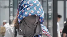 Seorang pejalan kaki mengenakan kain di atas kepalanya untuk melindungi diri dari panas dan terik matahari di Tokyo pada 5 Agustus 2025. (Kazuhiro NOGI/AFP)