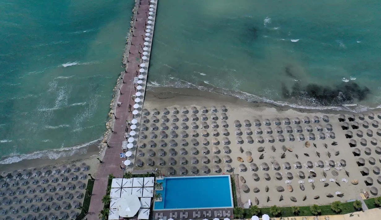 Foto udara pada 1 Juni 2020 menunjukkan payung-payung jerami di sebuah pantai di Qerret, dekat kota Kavaja, Albania. Rencananya pada 6 Juni mendatang, semua pantai umum akan dibuka untuk wisatawan setelah Albania menerapkan langkah-langkah pelonggaran pencegahan virus corona. (SHKULLAKU / AFP)