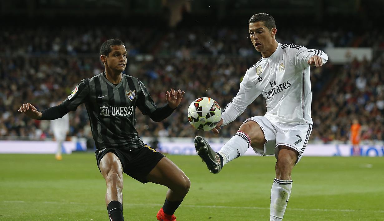 Cristiano Ronaldo coba mengelabui pemain Malaga Roberto Rosales dalam pertandingan yang berakhir dengan skor 3-1, Minggu (19/4/2015) dinihari WIB. (AP Photo/Andres Kudacki)