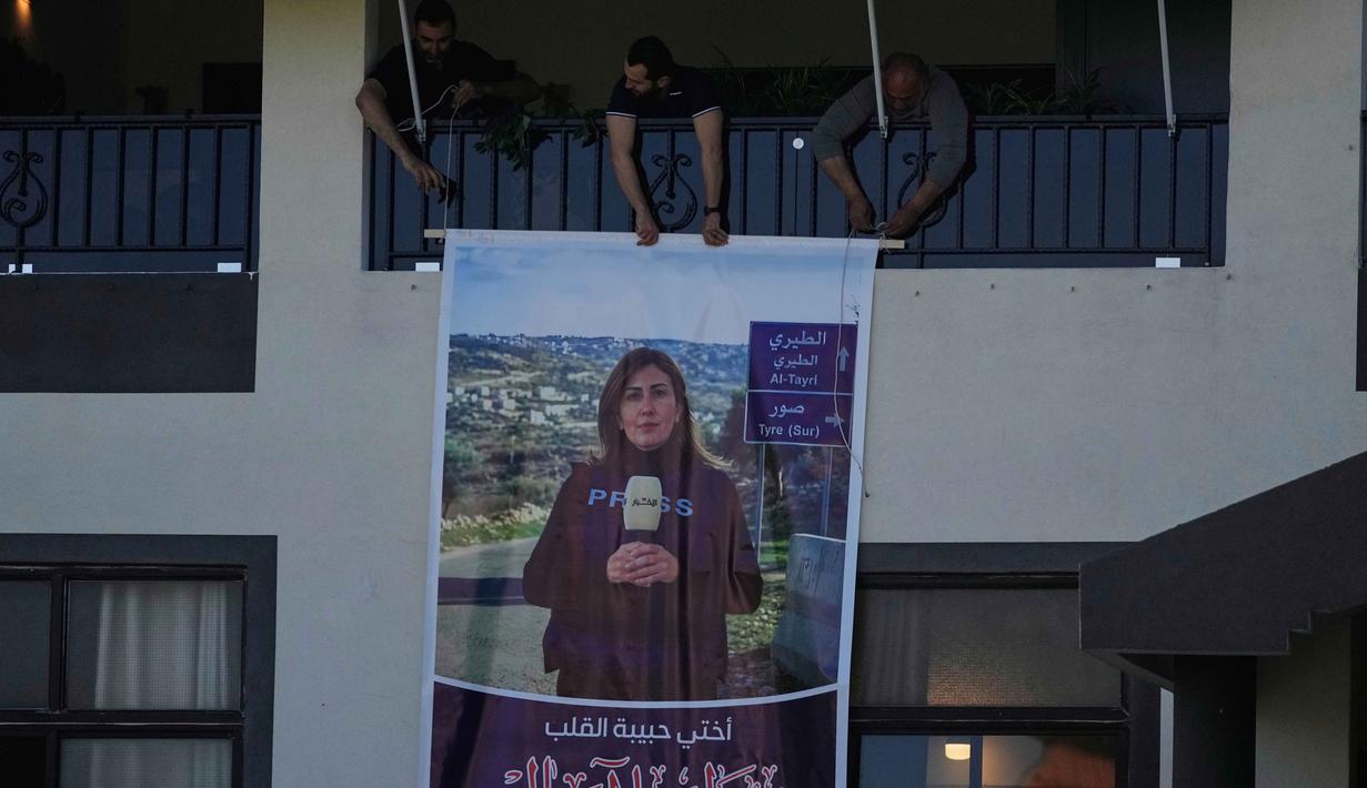 Sebulan sebelumnya, Maret 2026, tiga jurnalis Lebanon tewas dalam serangan Israel yang ditargetkan di kota Jezzine. Ketiganya adalab Ali Shoeib dari Al Manar TV serta Fatima Ftouni dan Mohamed Ftouni dari saluran Al Mayadeen. Tampak dalam foto, para pelayat menggantung poster raksasa yang menampilkan jurnalis Lebanon Amal Khalil yang tewas dalam serangan udara Israel pada Rabu 22 April 2026, di desa Baysariyeh, Lebanon Selatan, Kamis, 23 April 2026. (AP Photo/Mohammed Zaatari)