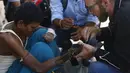 Pendiri Disaster Hack, Matthew Rockwell memasang tangan palsu buatan 3D ke lengan penderita kusta, Ram di Kathmandu (14/7). Tangan palsu yang dibuat dari mesin cetak 3 Dimensi (3D) jauh lebih murah dibandingkan tangan palsu Prostetis.(AFP Photo/Gopen Rai)