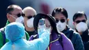 Petugas memeriksa suhu tubuh penumpang asing yang turun dari kapal pesiar Diamond Princess yang dikarantina di Yokohama, Jepang, Jumat (21/2/2020). Sebanyak 74 WNI berada dalam kapal pesiar Diamond Princess, empat di antaranya positif terjangkit virus corona (COVID-19). (AP Photo/Eugene Hoshiko)
