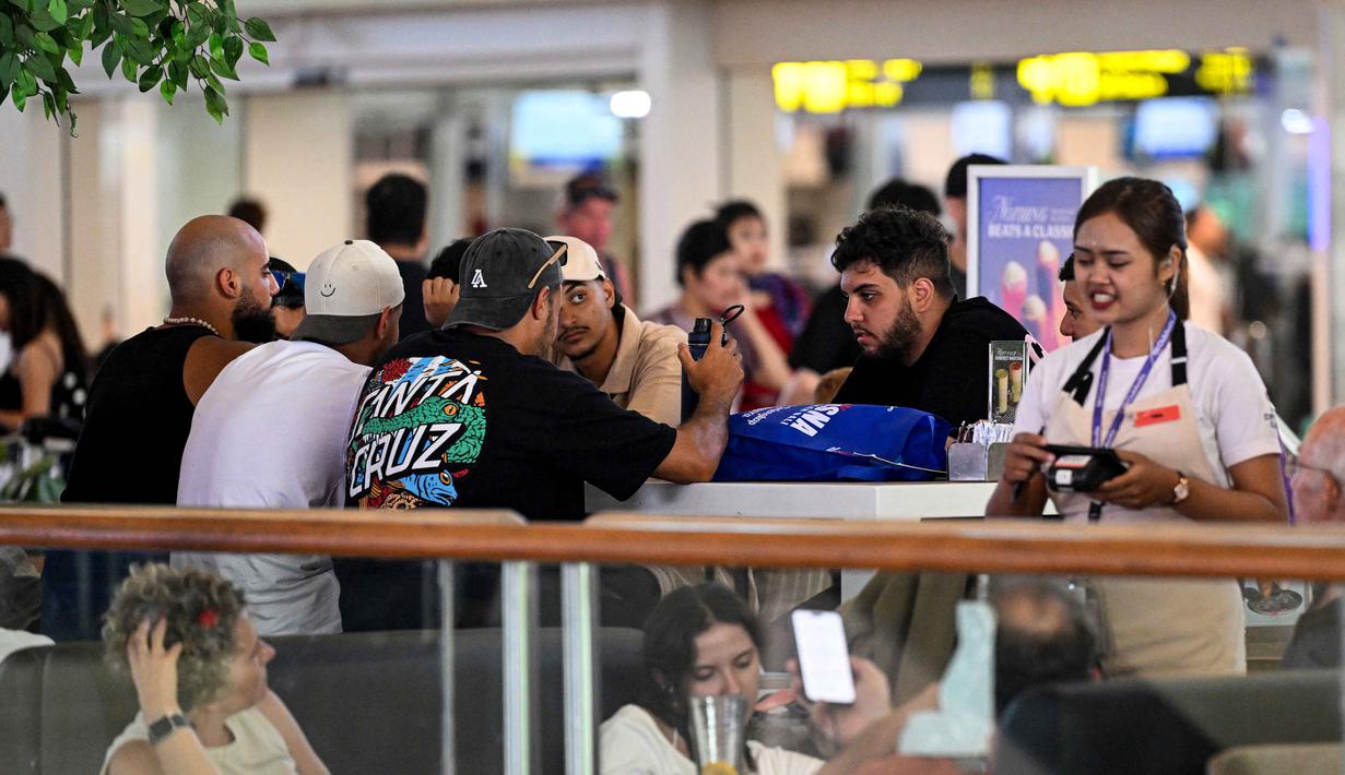 Di Bandara I Gusti Ngurah Rai, Bali, hingga Senin 2 Maret 2026 pukul 13.00 Wita, terdapat total 15 penerbangan rute internasional yang mengalami pembatalan penerbangan. Tampak dalam foto, para penumpang menunggu di tengah gangguan penerbangan akibat serangan Israel-Amerika Serikat terhadap Iran, di Bandara Internasional I Gusti Ngurah Rai, Bali, pada Senin 2 Maret 2026. (SONNY TUMBELAKA/AFP)