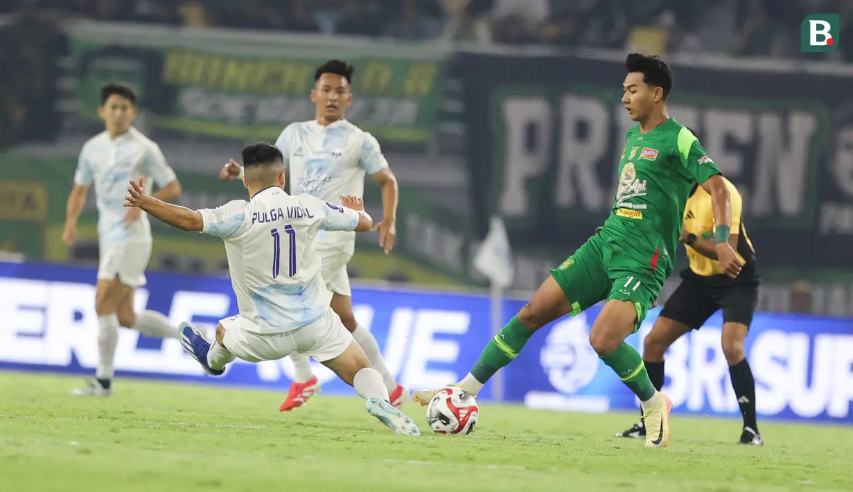 Pemain Persebaya Surabaya, Malik Risaldi (kanan) mencoba mengamankan bola dari pemain PSIM Yogyakarta pada pertandingan pembuka BRI Super League 2025/2026 di Stadion Gelora Bung Tomo, Jumat (08/08/2025) malam WIB. (Bola.com/Abdul Aziz)