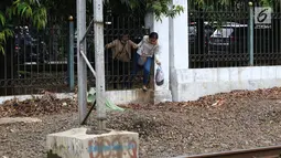 Warga menerobos pagar untuk menyeberangi rel kereta api di kawasan Lenteng Agung, Jakarta, Selasa (19/3). Tidak adanya JPO menyebabkan warga harus menerobos pagar besi, meskipun perilaku tersebut berbahaya bagi keselamatan.(Liputan6.com/Immanuel Antonius)