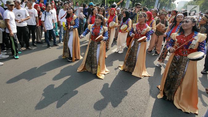 Warga menyambut antusias pawai obor Asian Para Games 2018 ketika melintas di kawasan Jakarta, Minggu (30/9). Nantinya api obor ini akan diarak di 17 titik lokasi di Ibu Kota. (Liputan6.com/Herman Zakahria)