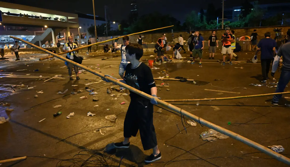 Seorang pria membersihkan bambu bekas barikade setelah demonstrasi menolak RUU ekstradisi di Hong Kong (13/6/2019). Lalu lintas telah dipulihkan di jantung Hong Kong sehari setelah bentrokan antara polisi dan pengunjuk rasa yang menolak RUU Ekstradisi . (AFP Photo/Hectro Retamal)
