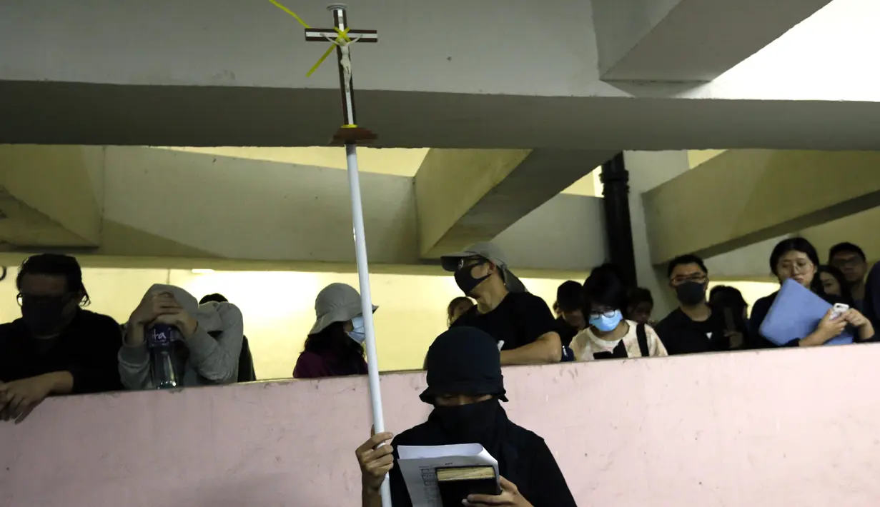Seorang pemrotes memegang sebuah tiang dengan salib di atas ketika mereka memberi penghormatan kepada mahasiswa Alex Chow Tsz-lok yang tewas di Hong Kong (8/11/2019). Chow dinyatakan meninggal pada Jumat pukul 8.09 pagi tadi.  (AP Photo/Dita Alangkara)