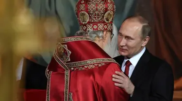  Presiden Rusia, Vladimir Putin memeluk kepala Gereja Ortodoks Rusia usai menjalani prosesi Paskah Ortodoks di Gereja Katedral Kristus Juru Selamat di Moskow, Rusia, (16/4). (AFP Photo / Vasily Maximov)