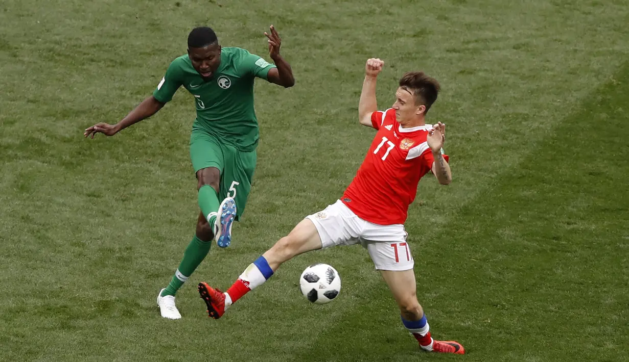 Aksi pemain Arab Saudi, Omar Othman (kiri) melepaskan tembaan saat diadang pemain Rusia, Alexander Golovin pada laga grup A Piala Dunia 2018 di Luzhniki stadium, Moskow, Rusia, (14/6/2018). Rusia menang 5-0. (AP/Darko Bandic)
