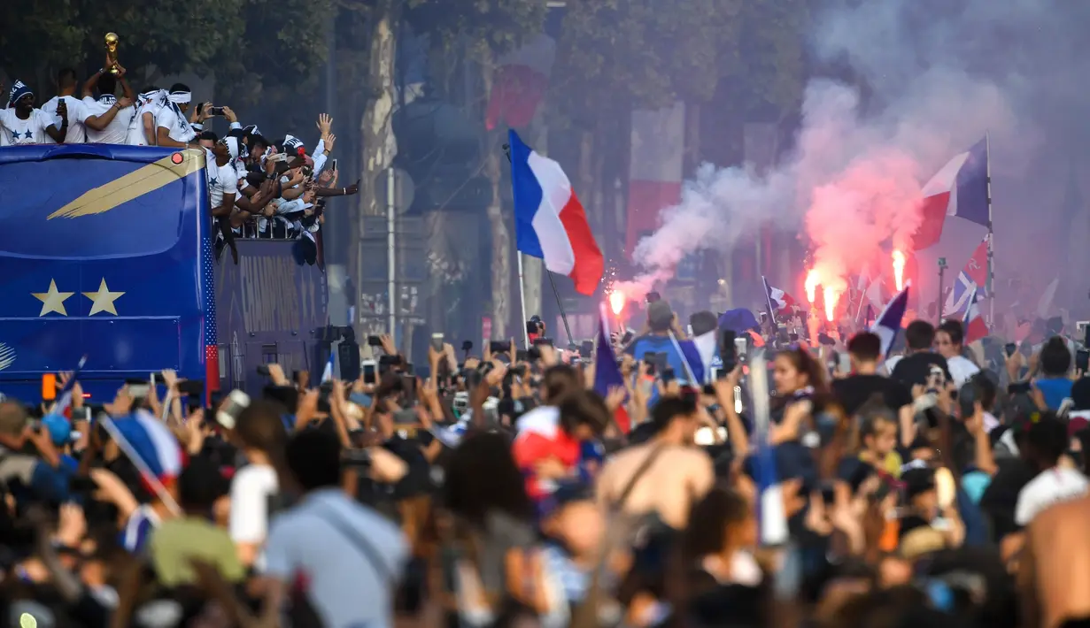 Timnas Prancis mengikuti pawai dengan bus atap terbuka merayakan juara Piala Dunia 2018 di jalan Champs Elysees, Paris, Senin (16/7). Prancis menggelar pesta besar penyambutan sekaligus parade kemenangan bagi skuad Les Bleus. (Eric Feferberg/Pool via AP)