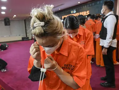 Petugas Imigrasi Indonesia mengawal tahanan di Kantor Imigrasi Jakarta pada Selasa 18 November 2025. Kantor Imigrasi Jakarta menggelar konferensi pers terkait penangkapan puluhan warga negara asing asal China. (BAY ISMOYO/AFP)