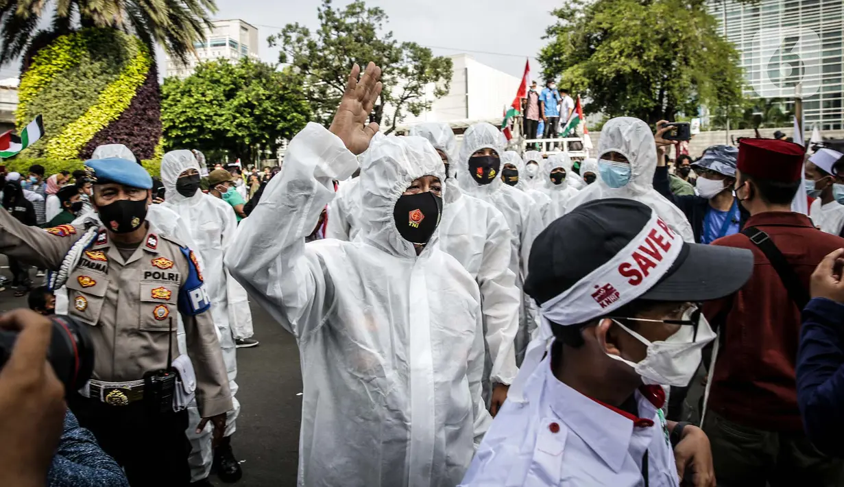 Petugas Satgas COVID-19 dari personel kepolisian menjaga protokol kesehatan peserta aksi solidaritas untuk Palestina di depan Kedutaan Besar Amerika Serikat, Jakarta, Selasa (18/5/2021). Massa mengutuk dan mengecam keras kekerasan yang dilakukan Israel atas Palestina. (Liputan6.com/Faizal Fanani)