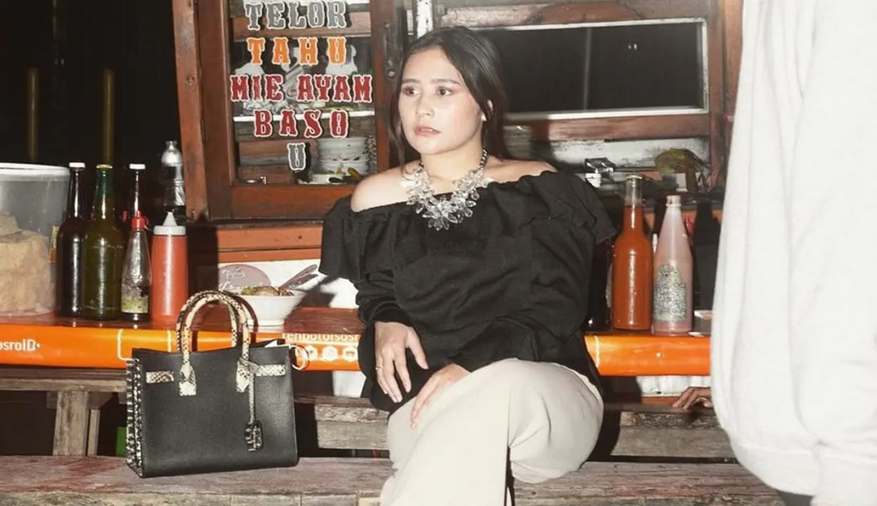 Saat melakukan pemotretan di pinggir jalan, Prilly juga sempat menggunakan busana off-shoulder berwarna hitam. Penampilannya ini ia tambahkan dengan kalung mewah serta tas berwarna senada. (Liputan6.com/IG/@prillylatuconsina96)