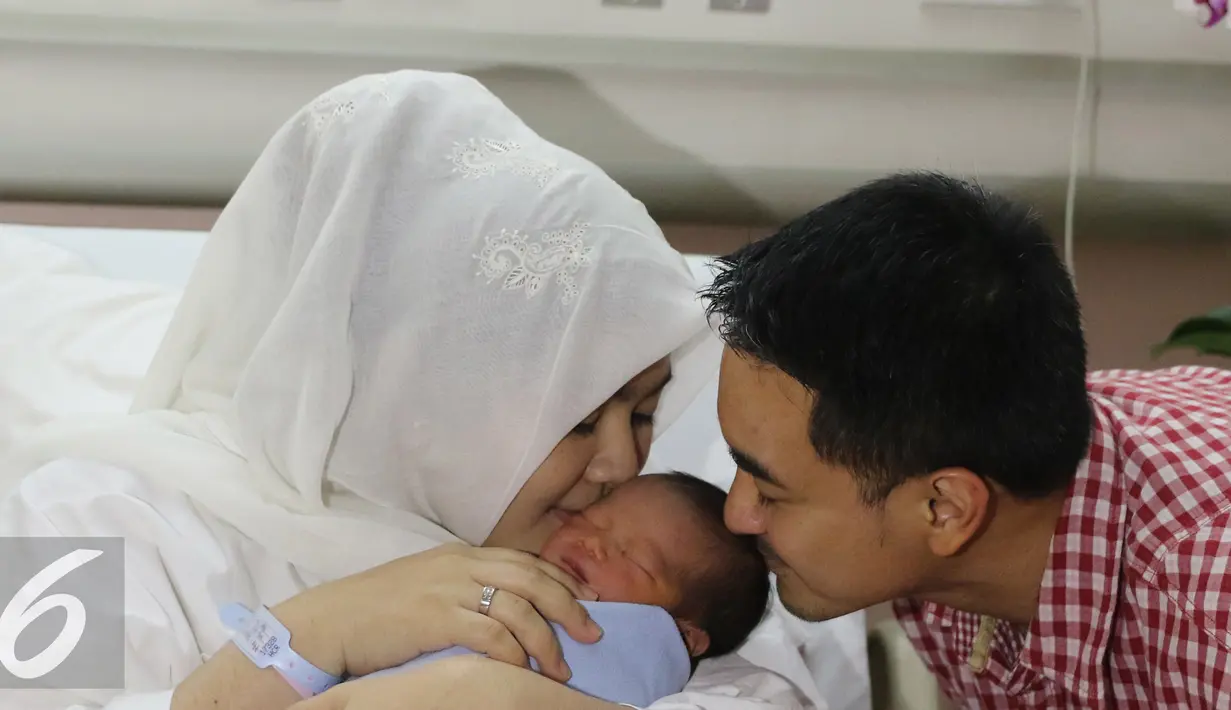 Gubernur Jambi Zumi Zola dan istri, Sherrin Tharia, mencium anak ke 2 mereka usai jumpa pres di Rumah Sakit kawasan Pondok Indah, Jakarta, Kamis (23/6). Anak ke 2 Zumi Zola lahir pada rabu (22/6) pukul 12.53. (Liputan6.com/Herman Zakharia)