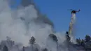 Sebuah helikopter pemadam kebakaran menjatuhkan air di Oak Fire di dekat Mariposa, California (23/7/2022). Api yang bergerak cepat membakar di luar Taman Nasional Yosemite telah memaksa evakuasi, menghanguskan lebih dari 11.500 hektar dan telah menghancurkan beberapa rumah sejak mulai Jumat sore. (Justin Sullivan/Getty Images/AFP)