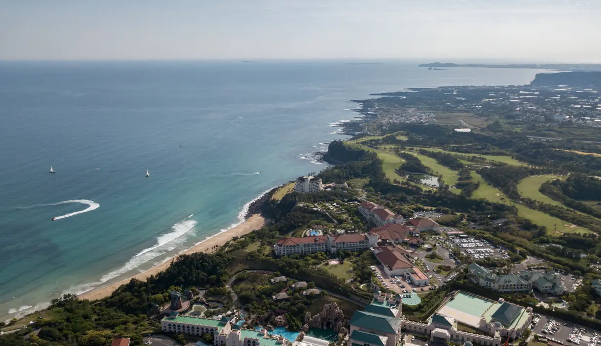 Pemandangan udara terlihat area resor pantai Jungmun di pulau Jeju, Korea Selatan (9/5/2019). Pulau ini bercuaca hangat sepanjang tahun dan pada musim dingin jarang turun salju, sehingga tanaman-tanaman yang tumbuh di daerah subtropis bisa bertahan hidup. (AFP Photo/Ed Jones)