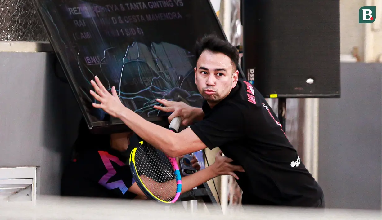 Selebritas Indonesia, Raffi Ahmad menabrak layar TV setelah berusaha mengembalikan bola ke arah pasangan Rezky Aditya dan Tanta Ginting pada laga tenis nomor ganda putra Turnamen Olahraga Selebriti Indonesia di GOR UNJ, Jakarta, Minggu (30/07/2023). Raffi yang berpasangan dengan Deddy Mahendra Desta menang dengan skor 4-6, 6-4, dan 6-4. (Bola.com/Bagaskara Lazuardi)