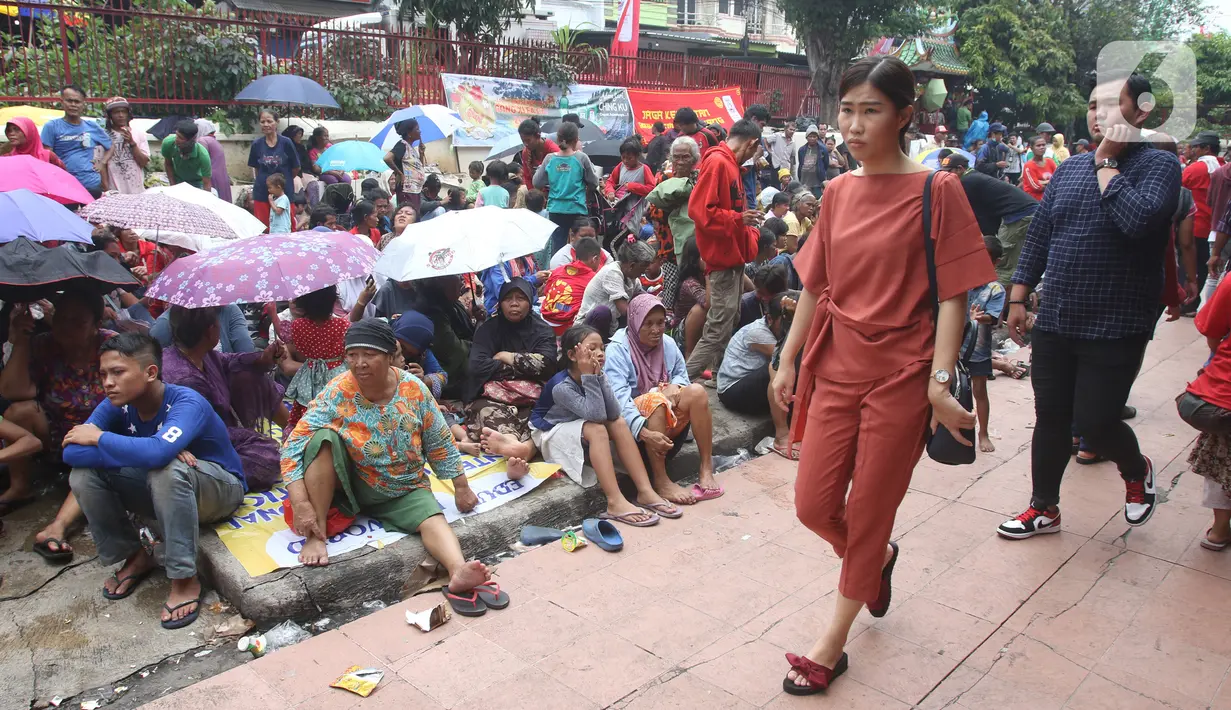 Warga keturunan Tionghoa melintas di depan pengemis yang menunggu sedekah Imlek di halaman Vihara Dharma Bhakti, Petak Sembilan, Jakarta Barat, Sabtu (25/1/2020). Pembagian sedekah tersebut dalam rangka berbagi dengan sesama ketika perayaaan Tahun Baru Imlek 2571. (Liputan6.com/Angga Yuniar)