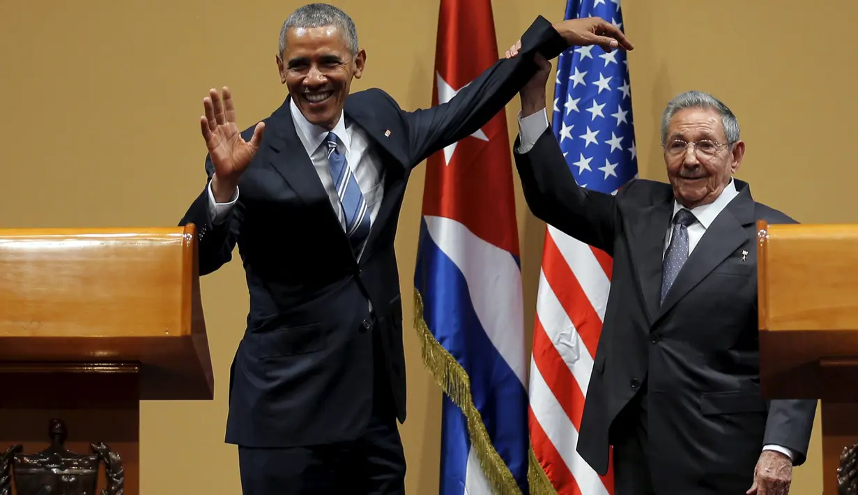 Presiden Kuba Raul Castro mengangkat tangan Presiden AS Barack Obama usai konferensi pers di Istana Revolusi, Havana, Senin (21/3). Obama menjadi presiden pertama AS yang berkunjung ke negara komunis itu sejak 88 tahun terakhir. (REUTERS/Carlos Barria)