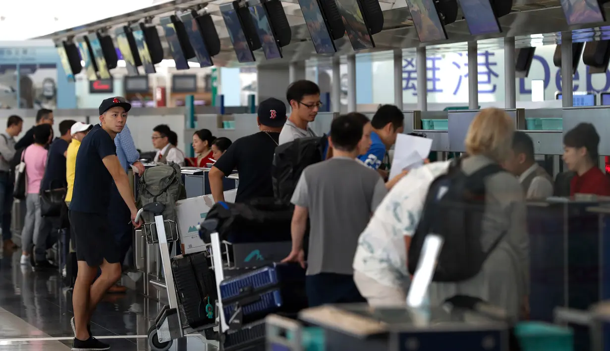 Calon penumpang pesawat memeriksa penerbangan mereka di bandara Hong Kong, Rabu (14/8/2019). Bandara Hong Kong kembali membuka penerbangan keberangkatan pada Rabu pagi setelah sempat lumpuh selama dua hari akibat demonstran menduduki salah satu bandara tersibuk di dunia tersebut. (AP/Vincent Thian)