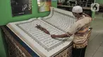 Petugas membersihkan Alquran raksasa koleksi Perpustakaan Jakarta Islamic Center (JIC), Jakarta Utara, Kamis (22/4/2021). Alquran raksasa tersebut merupakan pemberian dari Universitas Sains Alquran Wonosobo sebagai penghargaan atas berdirinya masjid JIC pada 2002. (merdeka.com/Iqbal S Nugroho)