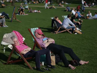 Warga Inggris berjemur di sebuah taman di pusat kota London,  Inggris, Sabtu (8/4). Sinar matahari yang hangat dimanfaatkan warga Inggris untuk berjemur dan bersantai dengan keluarga atau teman di taman-taman kota. (AFP PHOTO / Daniel Leal-Olivas)