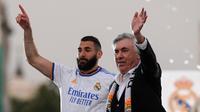 Pelatih Real Madrid, Carlo Ancelotti dan penyerang Karim Benzema melambai kepada suporter saat merayakan trofi La Liga Spanyol di alun-alun Plaza Cibeles di Madrid pada 30 April 2022. Real Madrid mengamankan gelar La Liga ke-35  setelah kemenangan kandang 4-0 atas Espanyol. (AFP/Oscar Del Pozo)