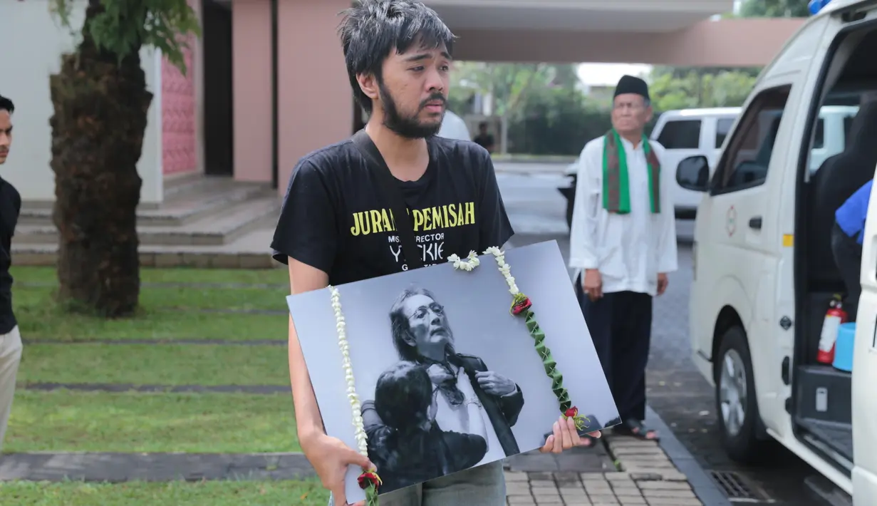 Kepedihan begitu terlihat dari salah satu anggota keluarga yang membawa foto Yokie. (Adrian Putra/Bintang.com)