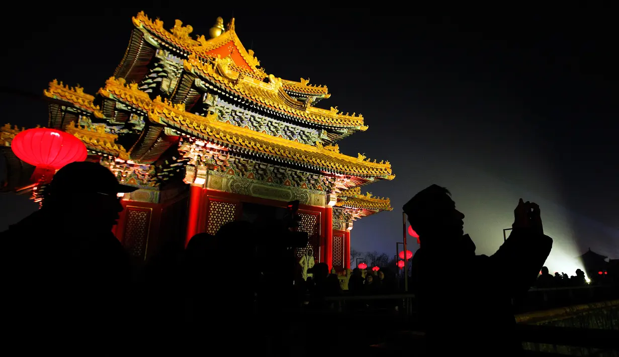 Siluet pengunjung terlihat ketika mengunjungi Kota Terlarang atau Forbidden City  yang diterangi pertunjukan cahaya selama perayaan Festival Lentera di Beijing, Selasa (19/2). Festival itu menandai berakhirnya liburan Tahun Baru Imlek (AP/Andy Wong)